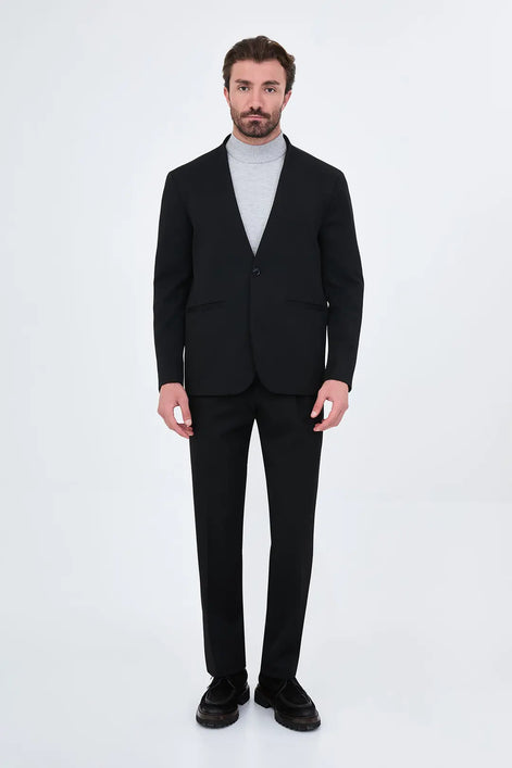 black two-piece suit with a light gray turtleneck sweater and black loafers