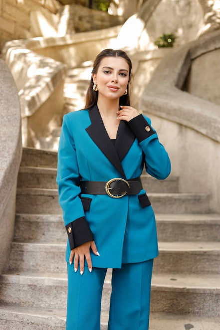 Woman in a blue suit standing on stone steps with a decorative wall in the background