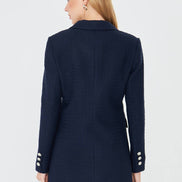 Navy blue coat with white buttons worn by a person on a white background