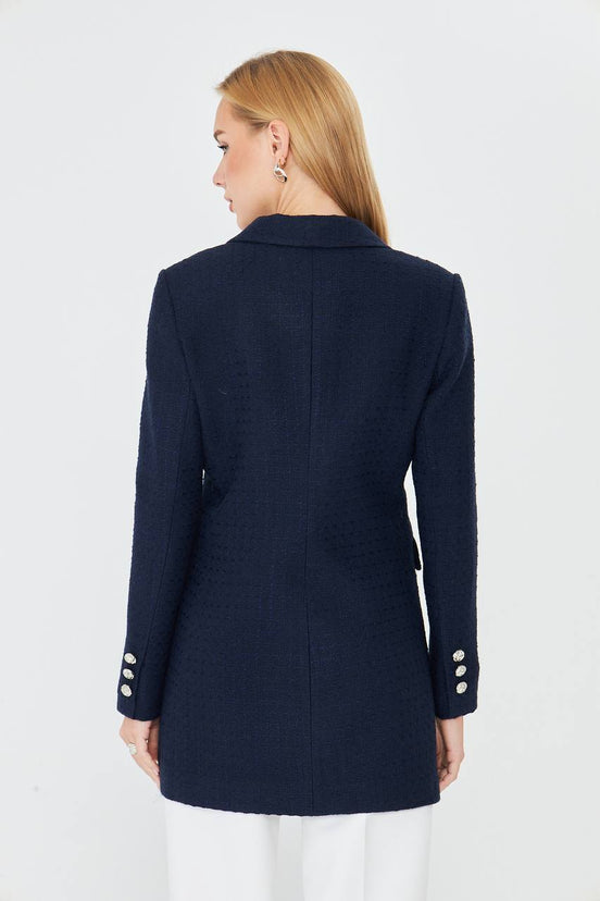 Navy blue coat with white buttons worn by a person on a white background