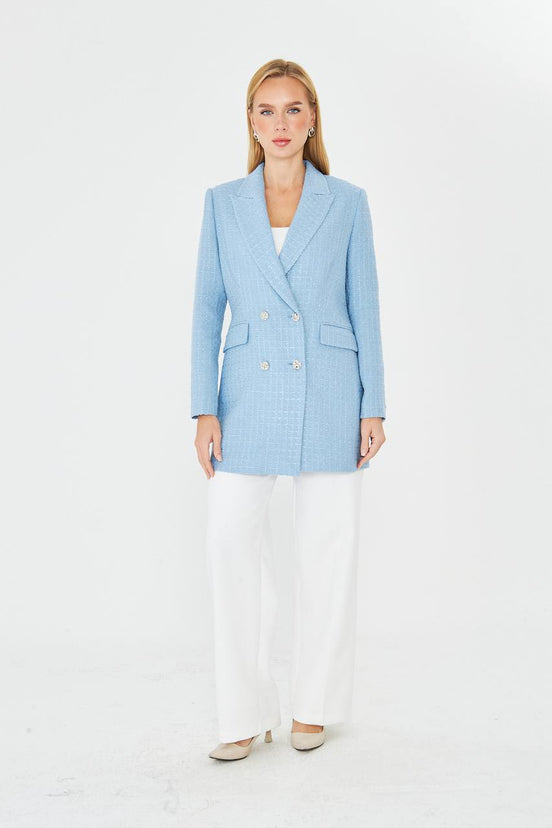 Woman wearing a light blue blazer over a white top on a white background